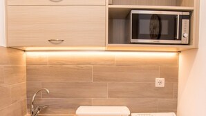 Een kleine keuken met een vaatwasser, een magnetron en een spoelbak.