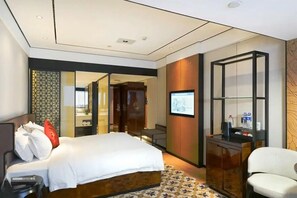 A hotel room with a bed, a desk, a chair, a TV, and a mirror. - Paco Hotel Zoo Metro Guangzhou (Guangzhou)