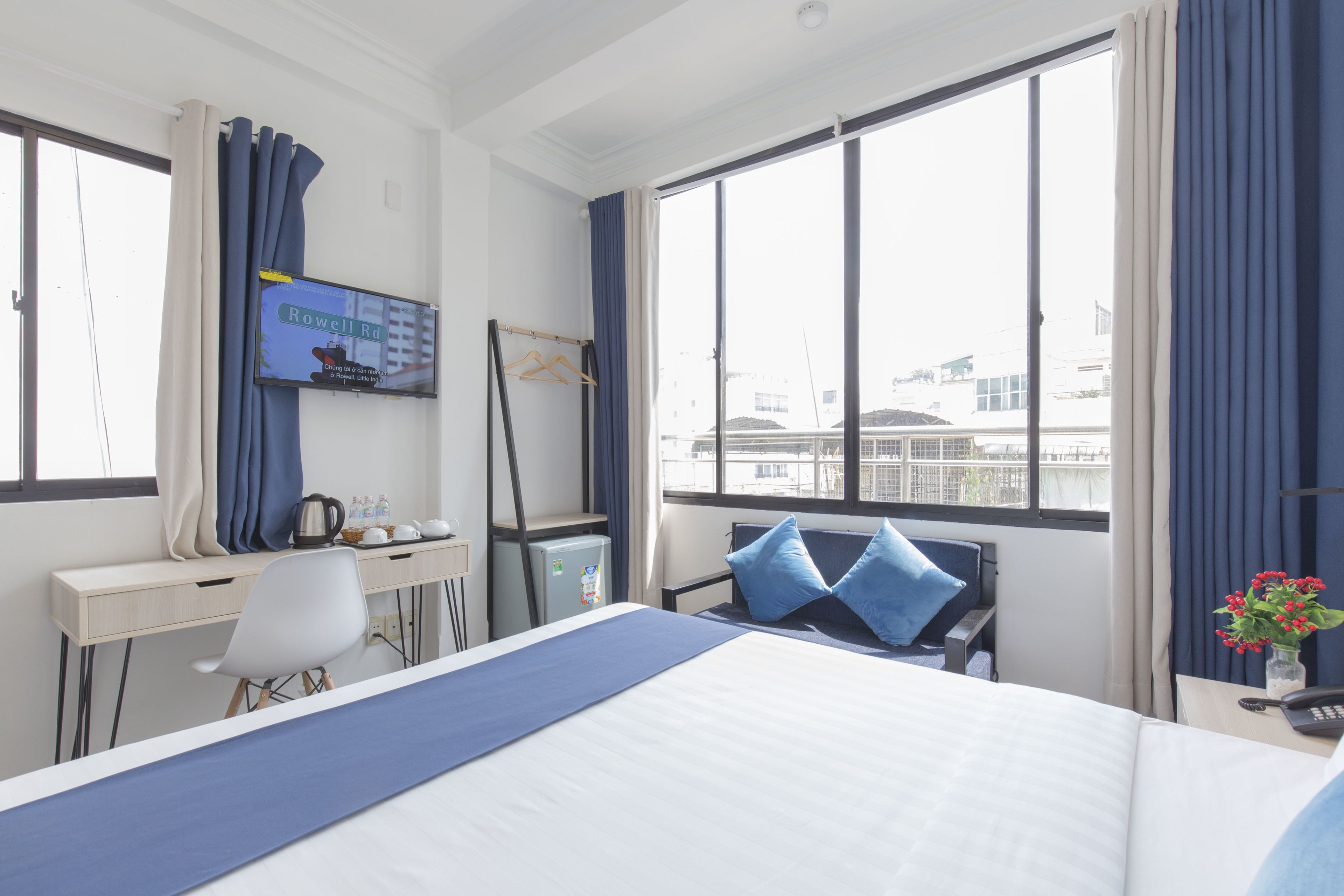 Ein Hotelzimmer mit Bett, Schreibtisch, Stuhl, Fernseher und einem fensterbepflanzten Fenster.