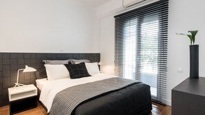 Ein modernes Schlafzimmer mit Bett, Nachttisch, Lampe und einer Zimmerpflanze.