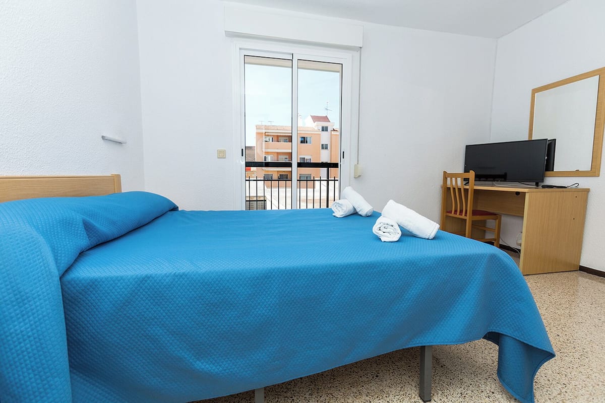 A hotel room with a bed, a desk with a computer, and a TV.