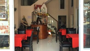 A restaurant with a central counter, red tablecloths, and black chairs. - Nguyen Minh Hostel (Cam Ly - Da Lat)