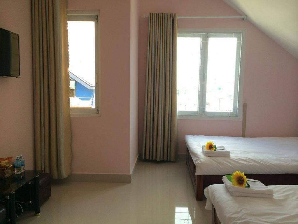 A hotel room with two beds, a television on the wall, and a window with curtains.
