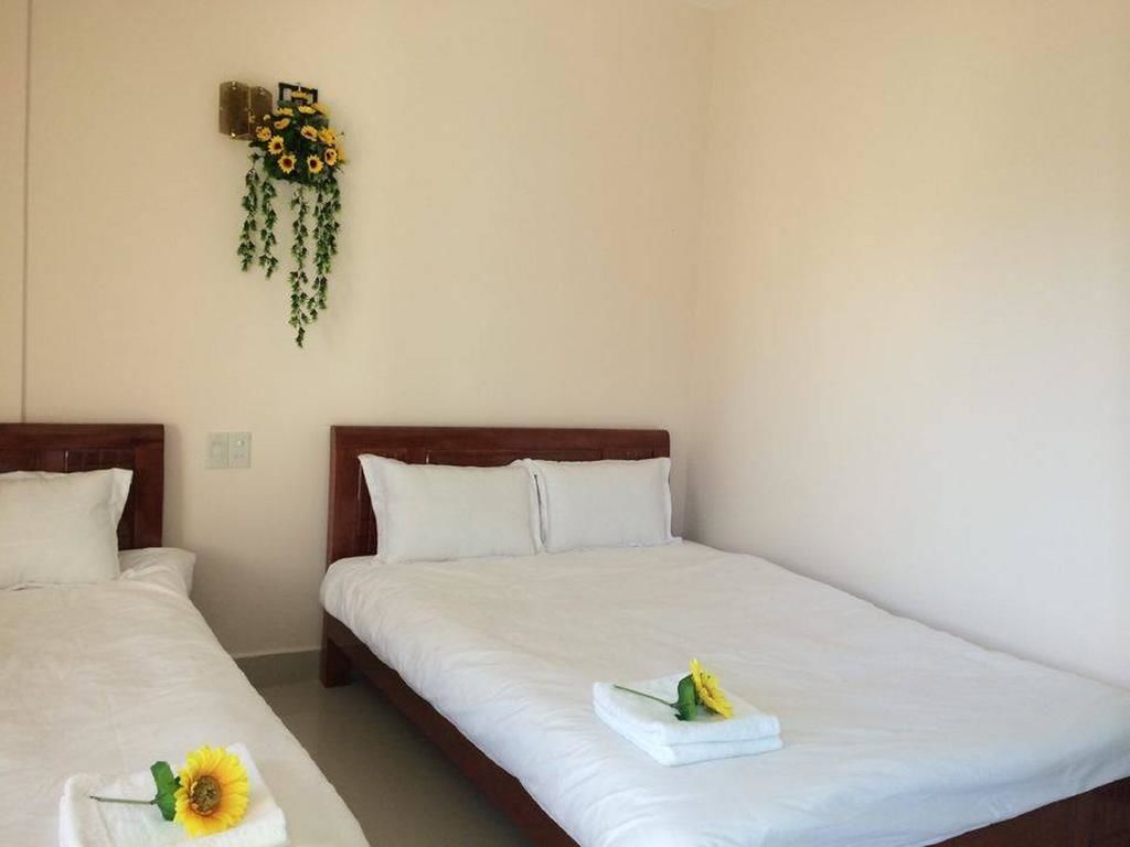 A hotel room with two single beds, white bedding, and a wall-mounted flower arrangement.