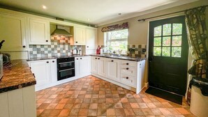 Une cuisine avec des meubles blancs, un pare-feu en carrelage et un sol à carreaux.