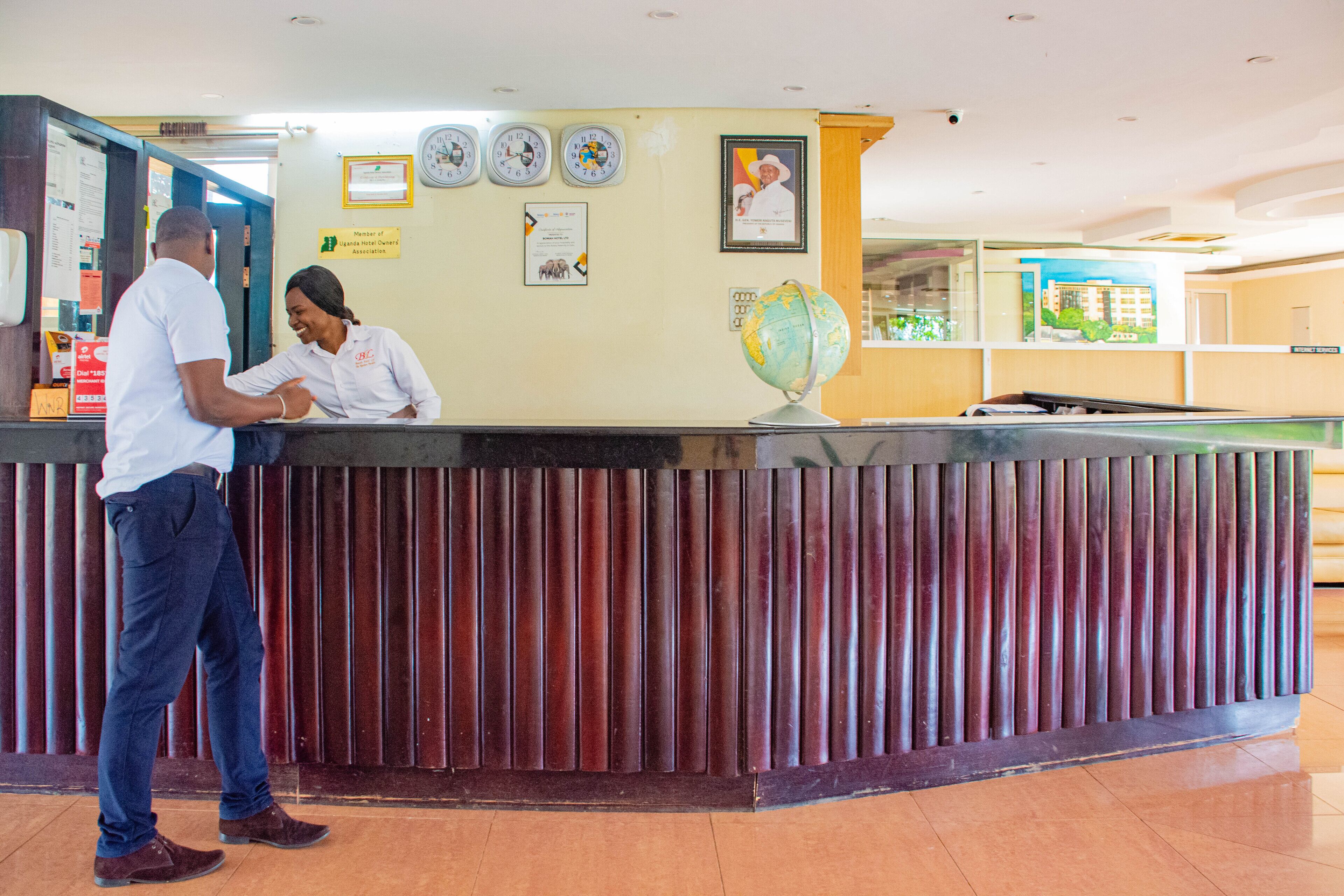 A reception desk with a wooden panel design, a globe decoration, and several framed certificates on the wall.