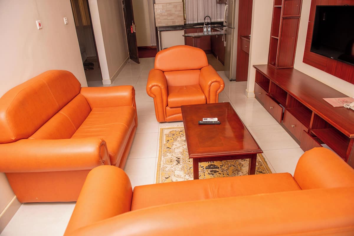 Una sala de estar con sofás de cuero naranja, una mesa de centro de madera y un televisor sobre un mueble de madera.