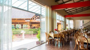 Un restaurante con amplios ventanales, mesas y sillas de madera.