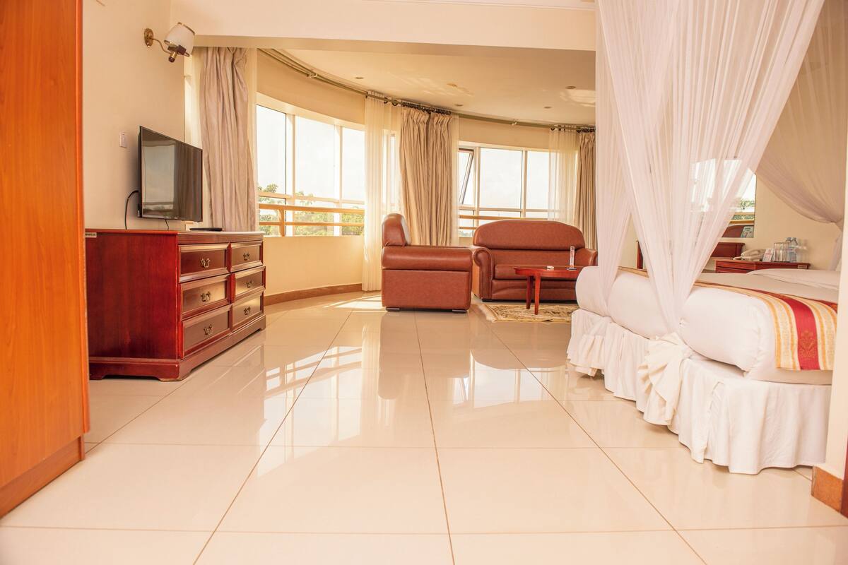 Una habitación de hotel con una cama, un televisor, un escritorio y una silla.