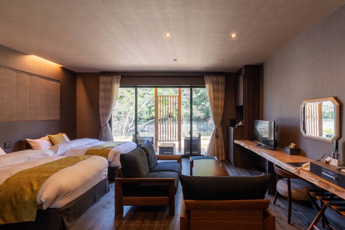 A hotel room with a bed, a desk, a chair, and a TV.