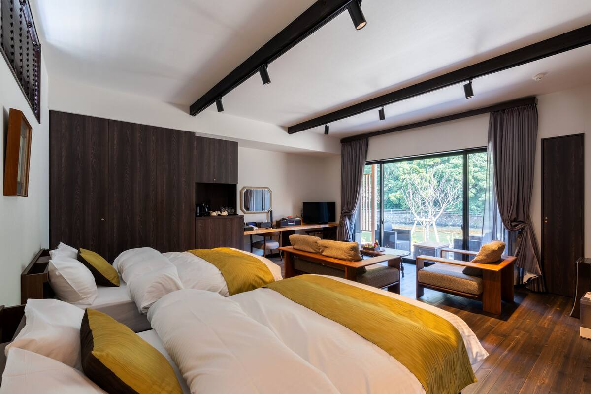 A modern hotel room with a large bed, a desk, a TV, and a view of the outdoors.