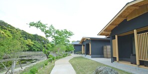 A modern building with a dark exterior, a wooden deck, and a pathway leading to the entrance. - Auberge Yusura (Ise)