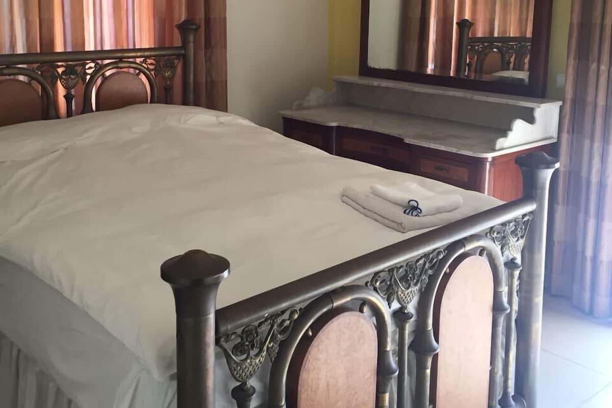 A bedroom with a bed, a dresser, a mirror, and an air conditioning unit.