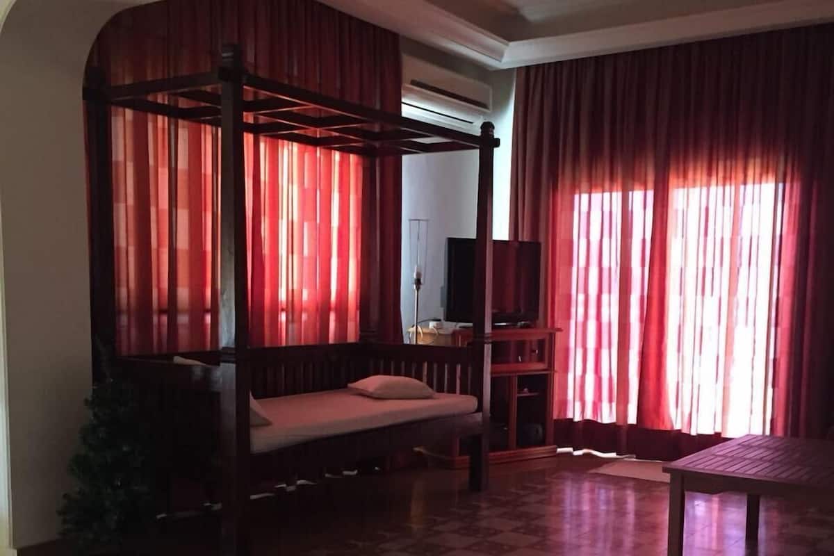 A room with a four-poster bed, a small table, and a television.