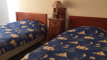 Una habitación con dos camas, una mesita de noche, una lámpara y una obra de arte en la pared.