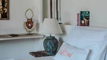 Una habitación de hotel ordenada con una cama, una lámpara, un objeto decorativo y un libro en una mesita de noche.