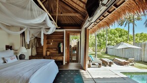 A bedroom with a bed, bedside table, lamp, and a view of the outdoor pool area. - Slow Private Pool Villas (Gili Air)