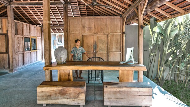 A wooden interior with a large table, benches, and a ceiling fan. - Slow Private Pool Villas (Gili Air)