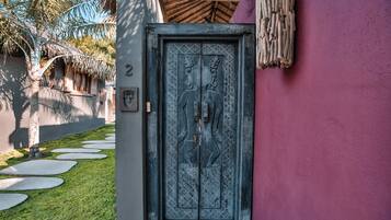 A door with intricate carvings, a number '2' sign, and a thatched roof structure in the background.