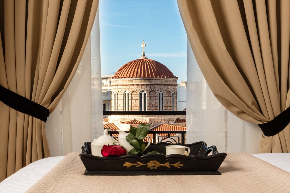 A hotel room with a view of a domed building through sheer curtains.