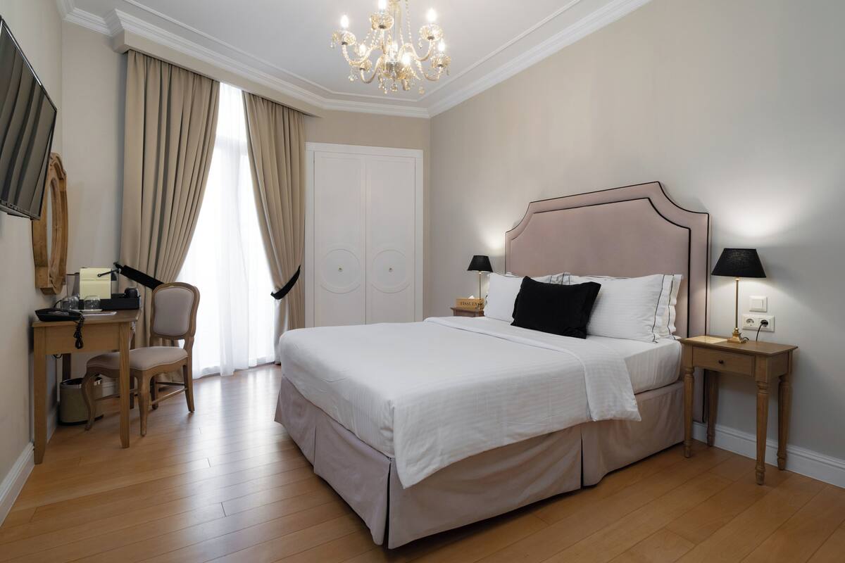 A neatly arranged bedroom with a large bed, bedside tables, a desk, and a chair.