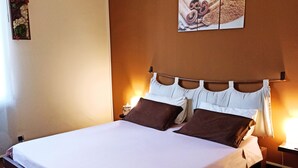A neatly made bed with a white mattress and brown headboard, a bedside table with a lamp, and a wall-mounted artwork above the bed. - Colazione da Augusta (Turin)