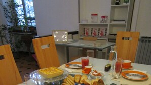 A breakfast table set with various dishes, including toast, a quiche, and a fruit platter. There are also several glasses of juice and a pitcher of water. - Colazione da Augusta (Turin)