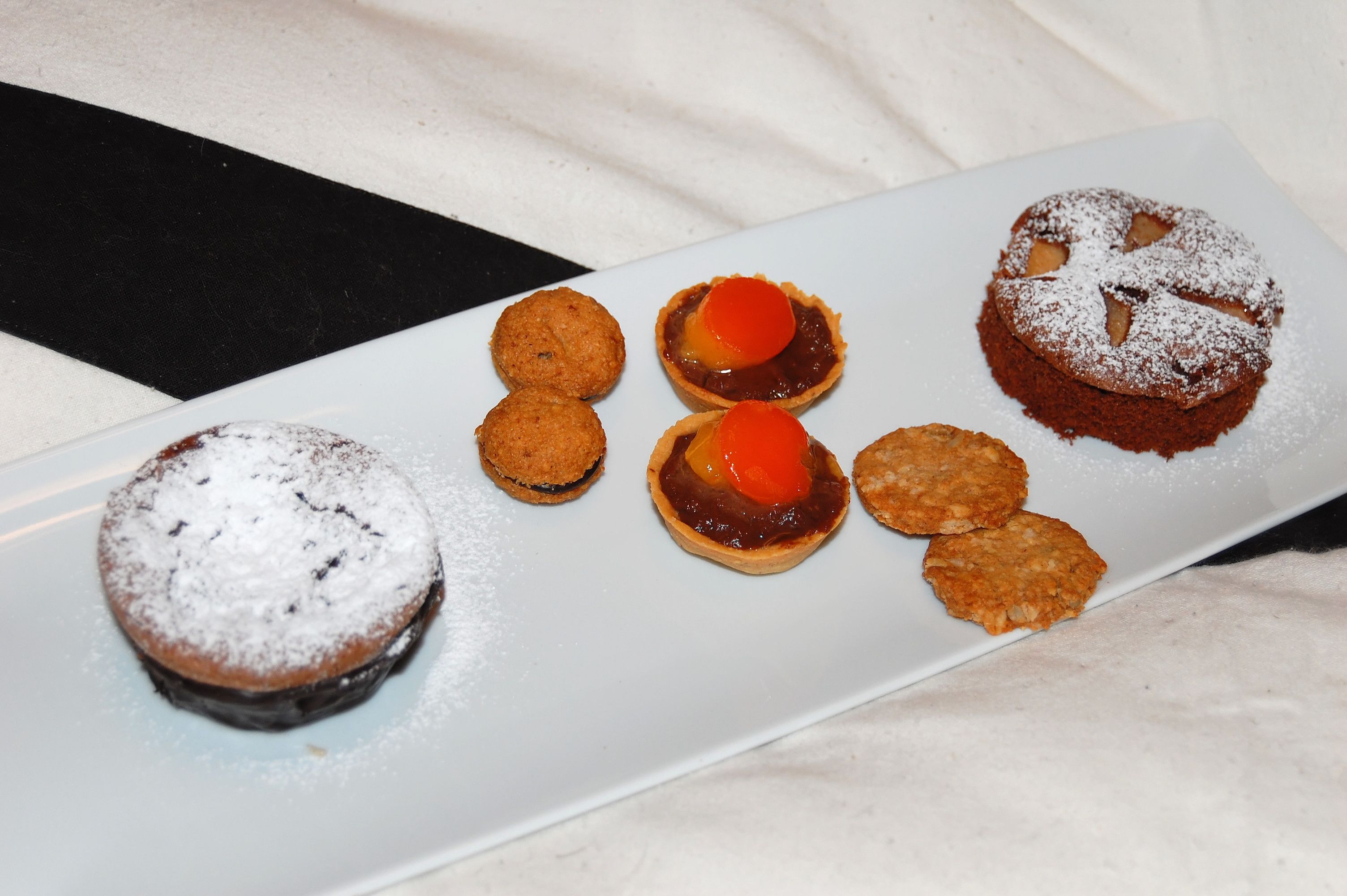 Un plato de postres con varias opciones, incluyendo pastel de chocolate, tartas y galletas.