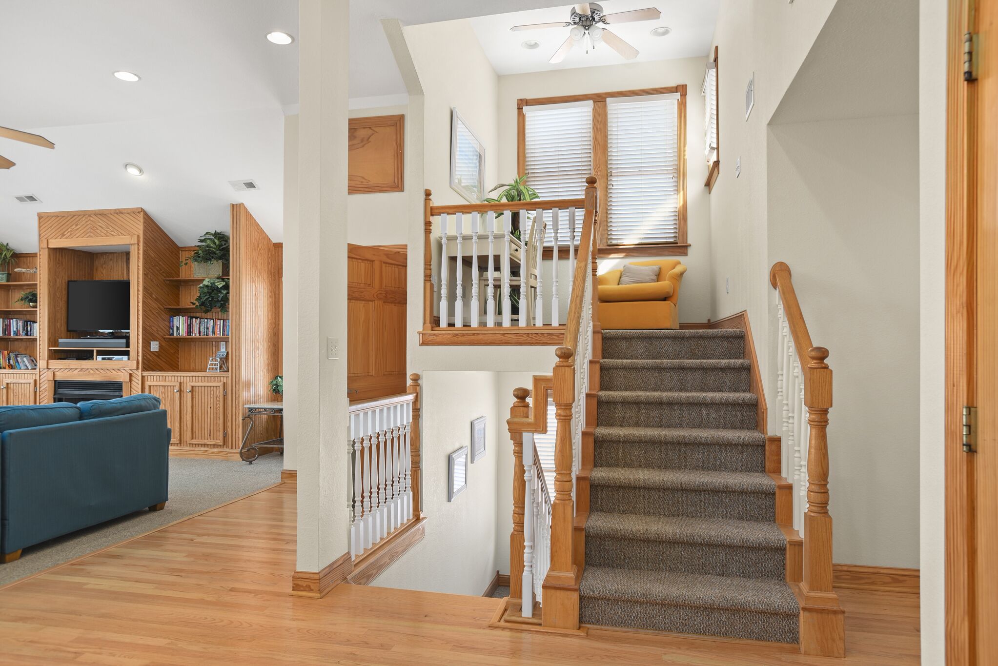 A spacious living area with a wooden staircase, a television, and a sofa.