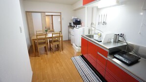 Una cocina compacta con comedor, que presenta un comedor de madera con sillas, una estufa integrada y un protector contra salpicaduras rojo.
