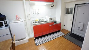 Cocina compacta con gabinetes rojos, microondas, fregadero y refrigerador.