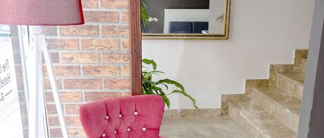 Un intérieur moderne avec un fauteuil rouge, une table basse en bois, un mur en briques et un escalier.