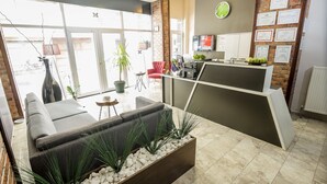 A reception area with a modern desk, seating, and a clock on the wall. - The Corner Inn Hotel Suit (Eskisehir)