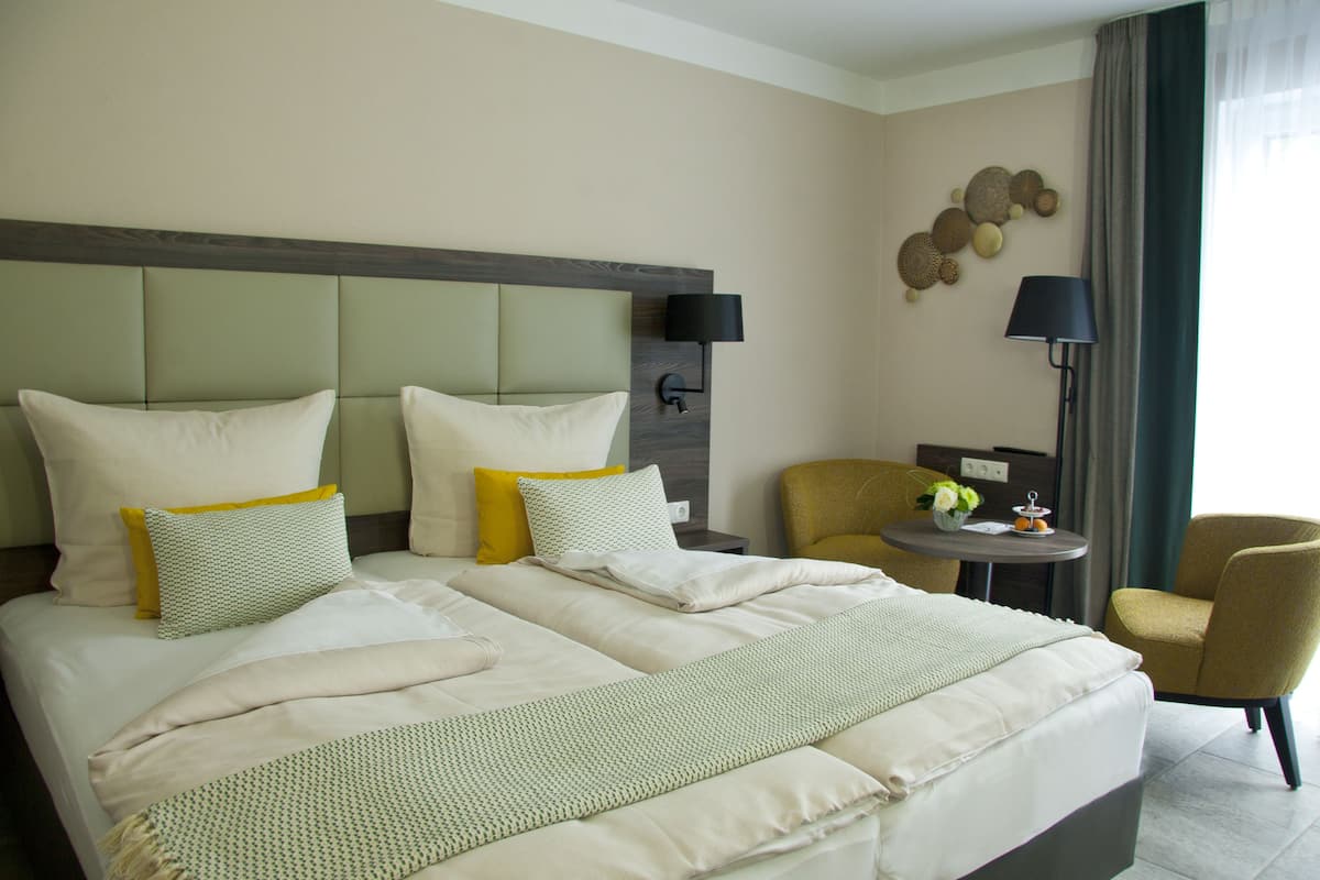 A hotel room with a large bed, two bedside tables, a chair, and a lamp.