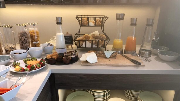 Un buffet de petit-déjeuner proposant une variété d’aliments, un coin café et un assortiment d’assiettes et de bols.