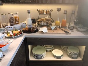 A breakfast buffet with various food items, a coffee station, and a selection of plates and bowls. - Hotel Am Moosrain (Eitting)