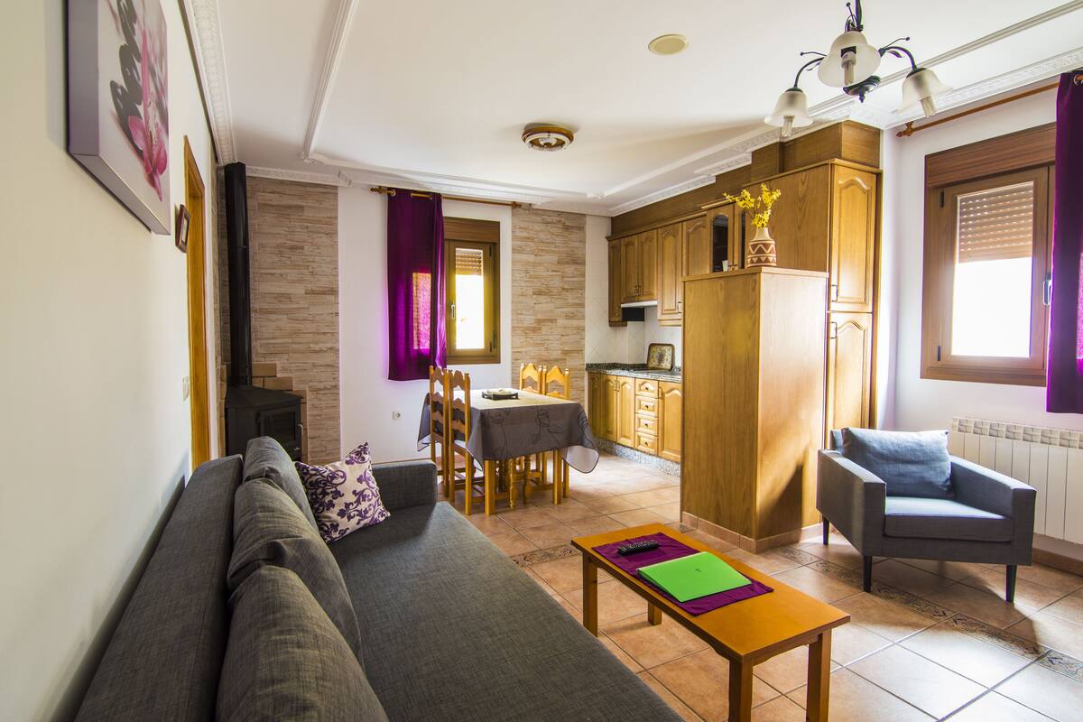 Un salon comprenant un canapé, une table à manger, un coin cuisine et une chaise.