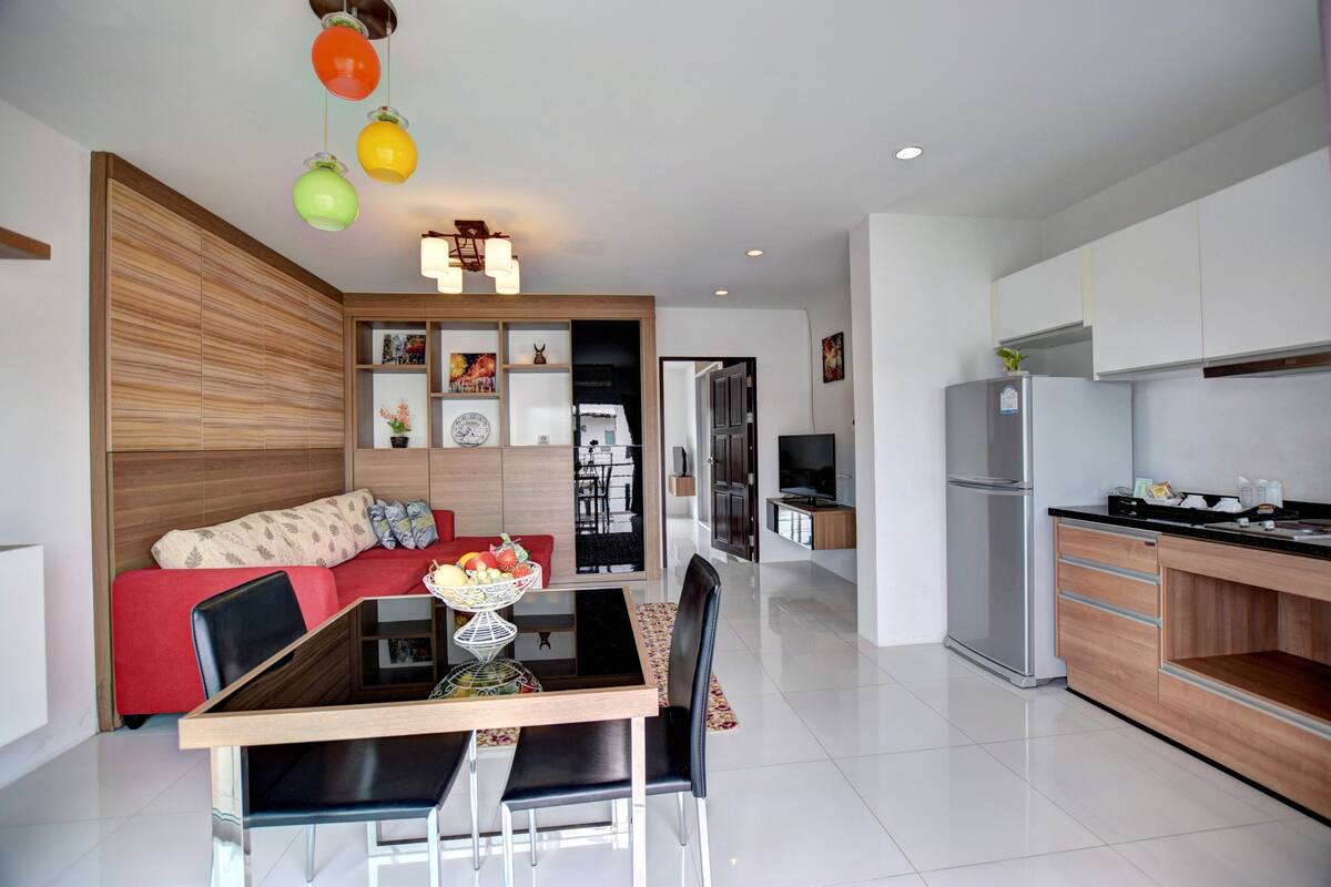 A modern kitchen with a refrigerator, stove, and dining area with a table and chairs.
