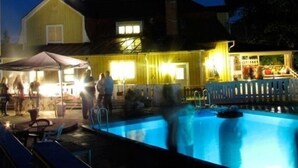 Un espace piscine doté d’un coin salon abrité et d’un bâtiment en arrière-plan.