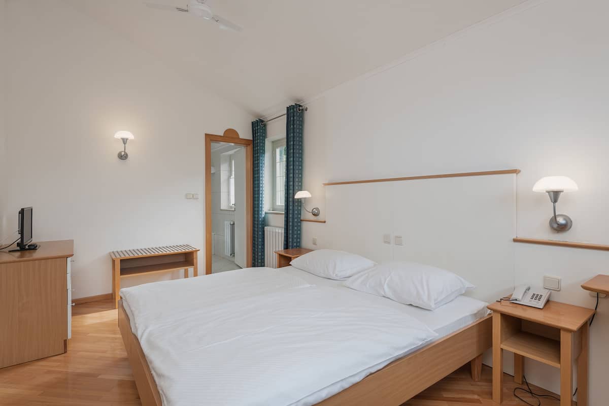 Une chambre moderne avec un lit en bois, des tables de chevet, un bureau et un miroir.