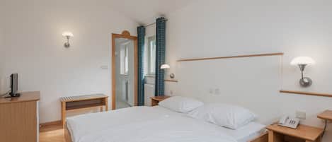 A modern bedroom with a wooden bed, bedside tables, a desk, and a mirror.