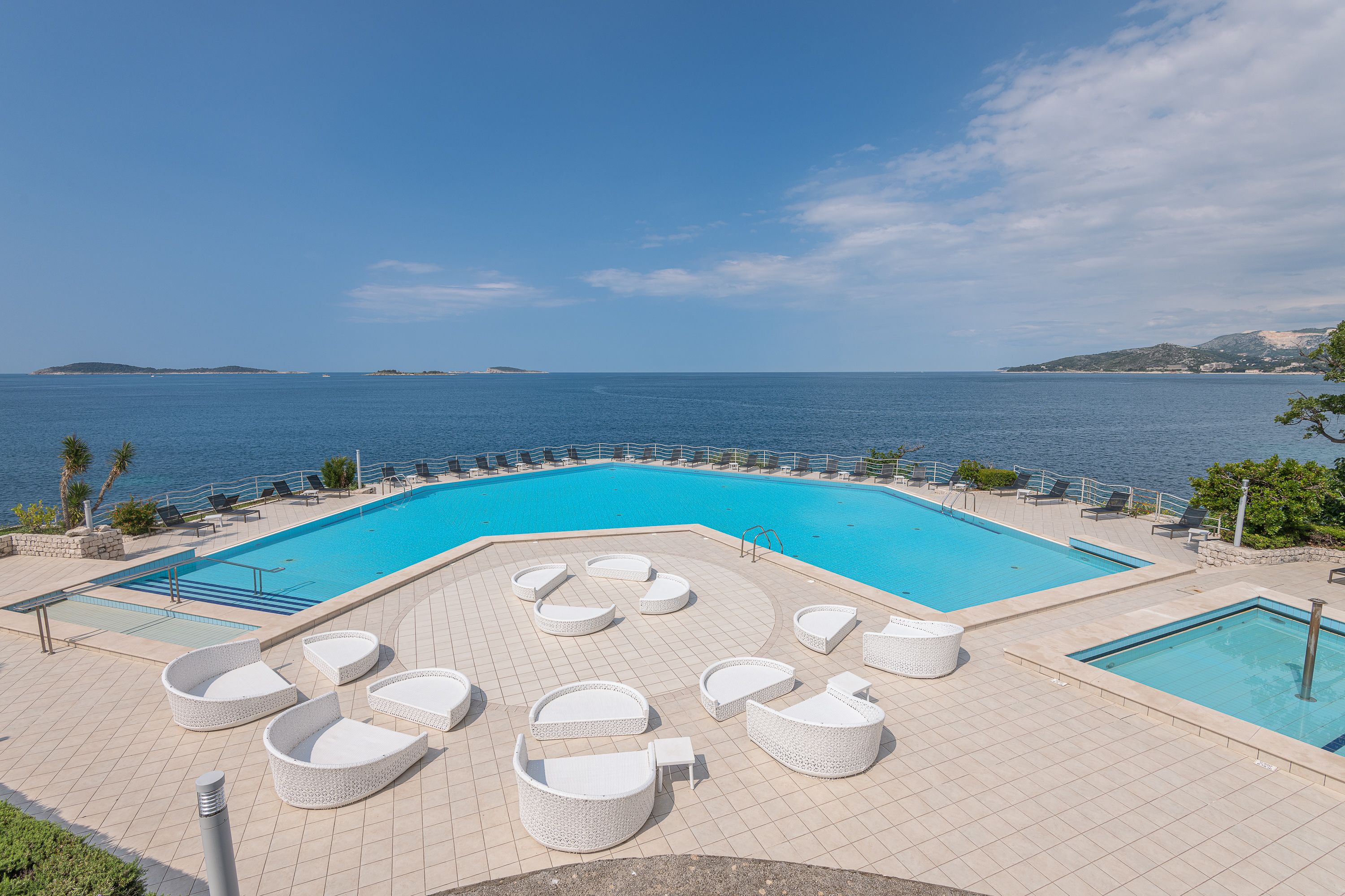 Zona de piscina con sillones de descanso y vista al mar.