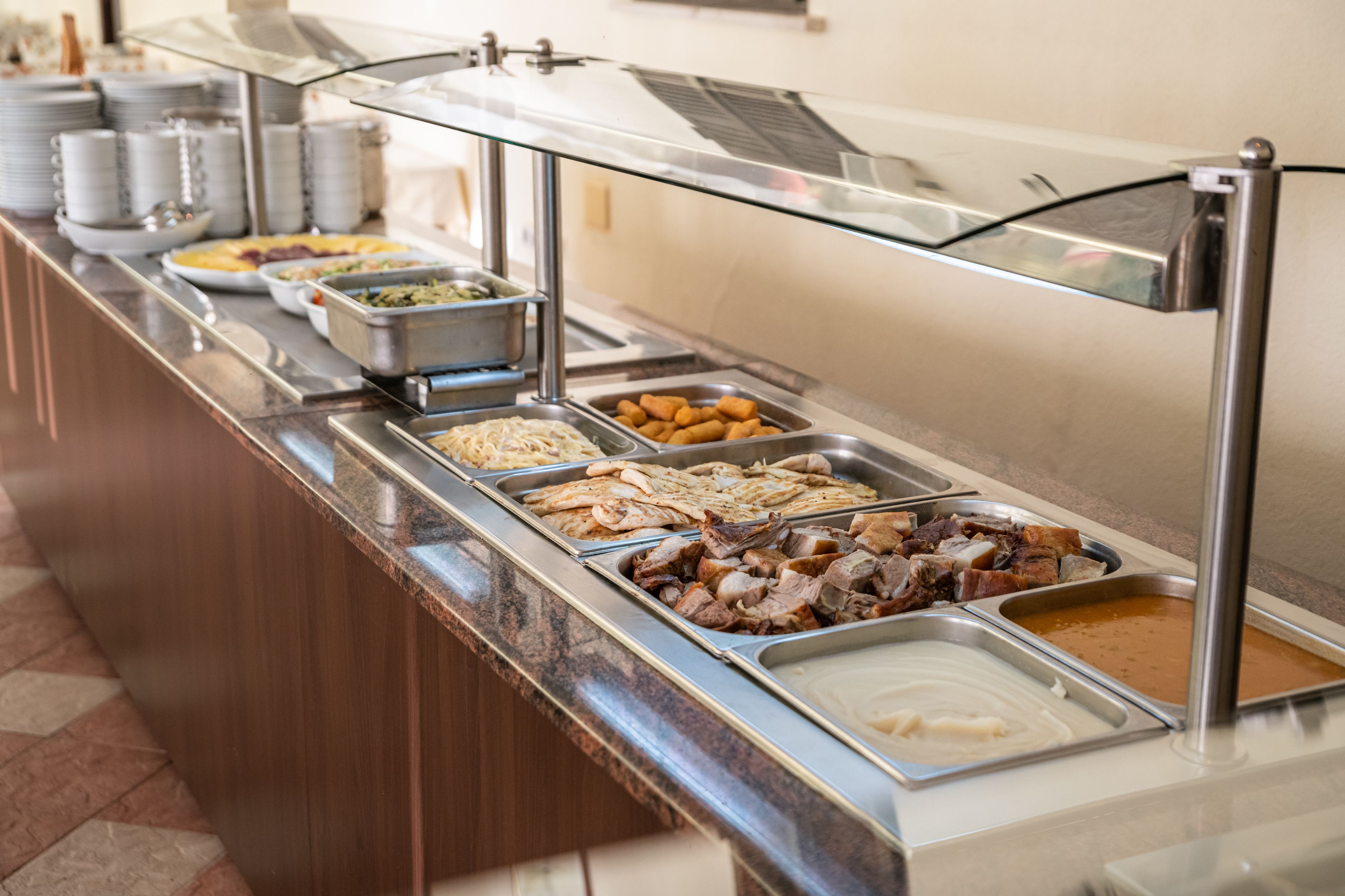 Un bufé con diversas opciones de comida, incluyendo carnes, verduras y salsas.
