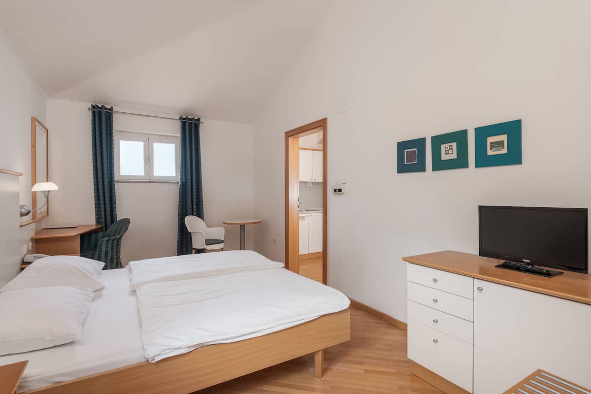 Une chambre d’hôtel équipée d’un lit, d’un bureau, d’une chaise, d’une télévision et d’une armoire.