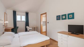 A hotel room with a bed, a desk, a chair, a television, and a wardrobe.