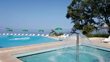 Una piscina al aire libre, sillones reclinables de piscina