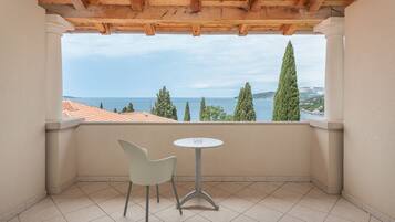 A balcony with a view of the sea, a table, and a chair.