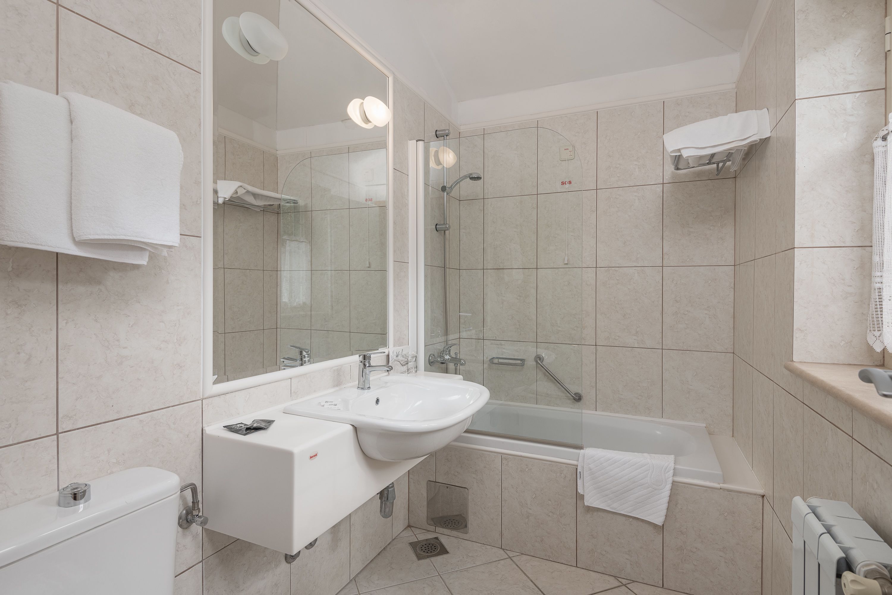 Un baño moderno con lavamanos, espejo y bañera.