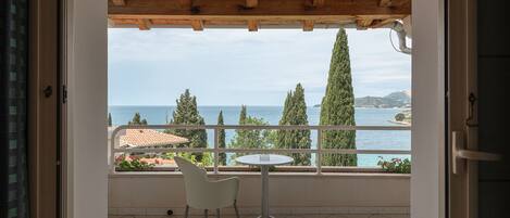 Un balcón con vista al mar, una mesa y una silla.