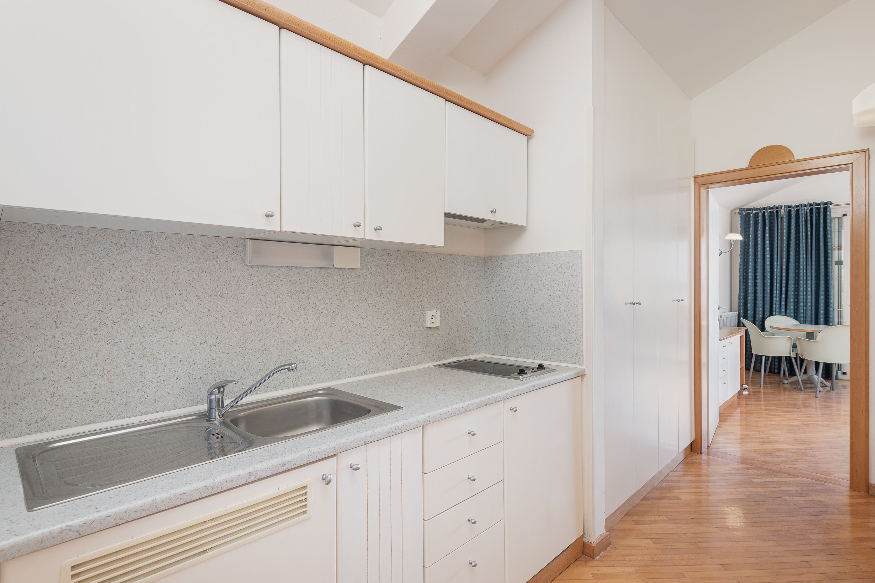 A modern kitchen with white cabinets, a granite countertop, and a double sink.